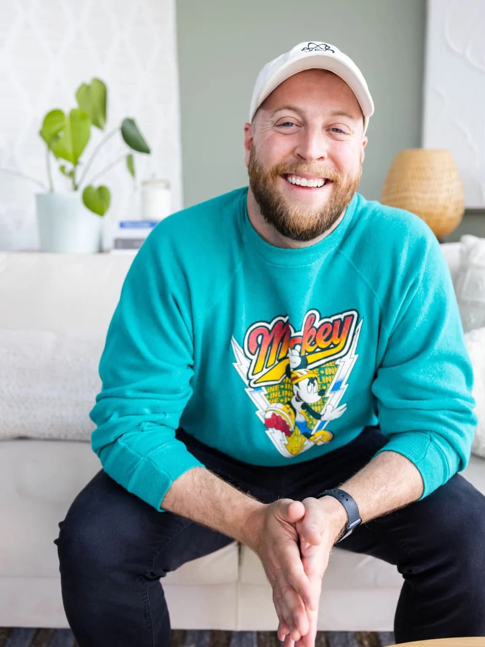 Jay Clouse smiling on a couch in a teal sweatshirt